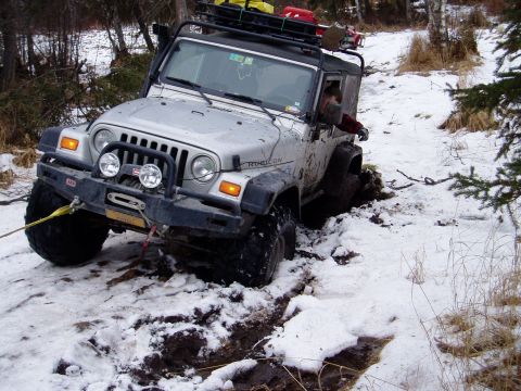 2000 Ford E350 - This Jeep Wrangler Rubicon is stuck in the snow and mud, with a tow strap attached to the front bumper.