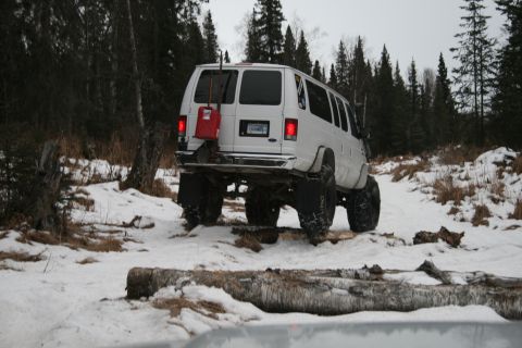 2003 Jeep TJ - A white van navigates a snowy trail, with a red gas can attached to its rear for extended journeys.