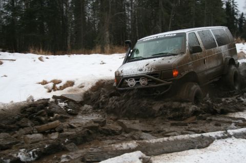 2003 Jeep TJ - This van is navigating a challenging muddy terrain with snow visible in the background.