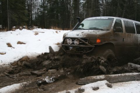 2003 Jeep TJ - A van navigates a challenging muddy and snowy terrain with a snorkel and brush guard.