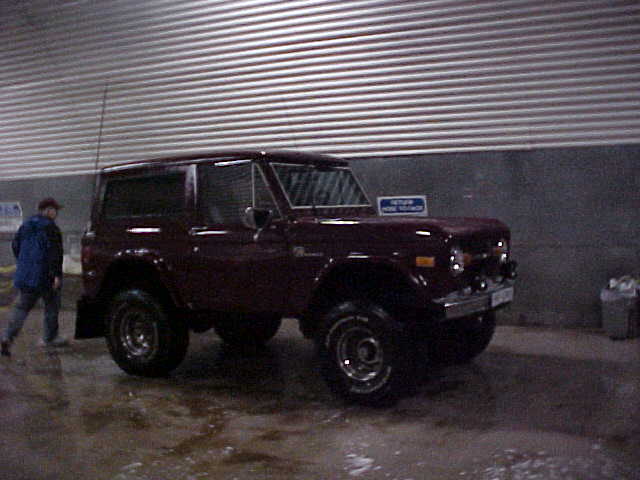 Dark red SUV parked indoors with a person walking by