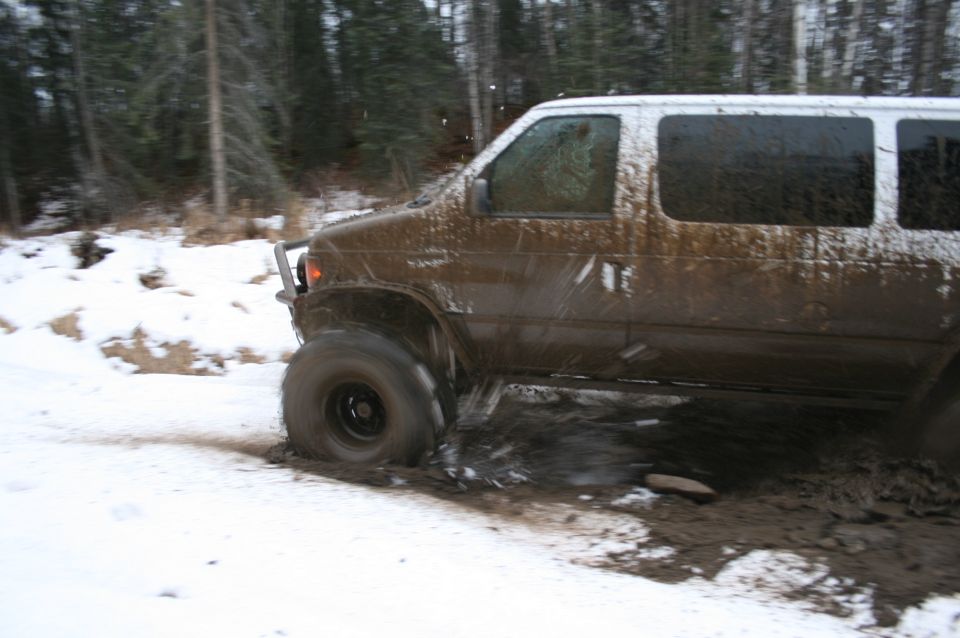 van stuck in mud and snow, trees in background