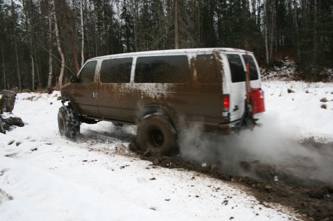 2003 Jeep TJ - A van struggles off-road in snowy and muddy conditions, its tires churning the terrain.