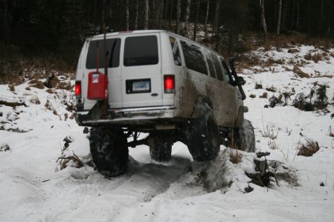 2003 Jeep TJ - A white van navigates a snowy trail with its large off-road tires.