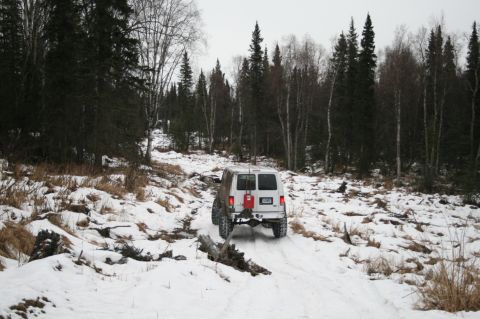 2003 Jeep TJ - White van navigates a snowy path through a wooded area in winter.