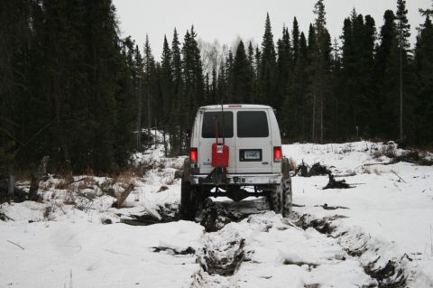 2003 Jeep TJ - A white van navigates a challenging snowy terrain, with a red gas can mounted on its rear.