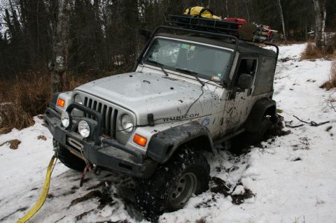 2003 Jeep TJ - This 2003 Jeep TJ is stuck in a snowy, muddy ditch with a winch line attached.