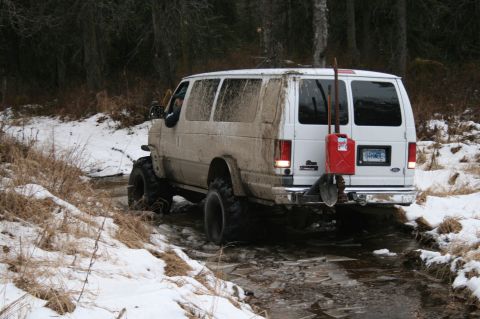2003 Jeep TJ - This modified van navigates a challenging off-road path covered in snow and mud.