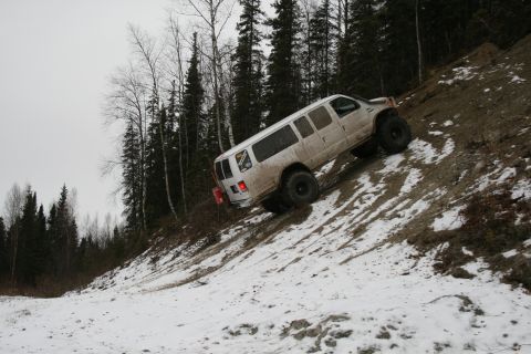 2003 Jeep TJ - Van with large tires navigates a challenging snowy and muddy incline.