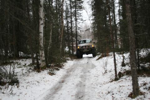 2003 Jeep TJ - A tan Jeep TJ navigates a snowy forest road during winter.