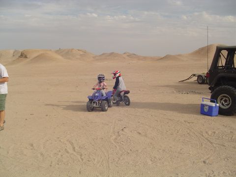 2000 Jeep TJ - Children enjoy riding ATVs and dirt bikes in a desert environment, with a Jeep and trailer nearby.