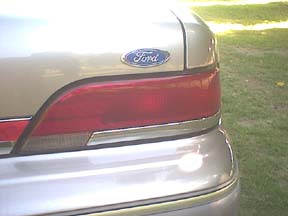 1994 Ford Crown Victoria - Close-up of the rear of a gold 1994 Ford Crown Victoria, showing the taillight and Ford emblem.