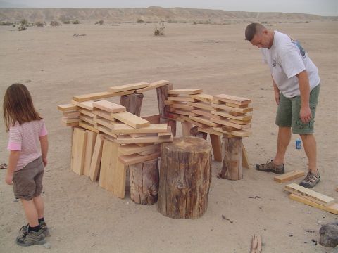 2000 Jeep TJ - Two people are constructing a wooden fort-like structure in a barren, sandy environment.