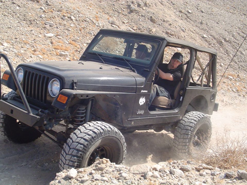 Black 2000 Jeep TJ off-roading on a rocky trail