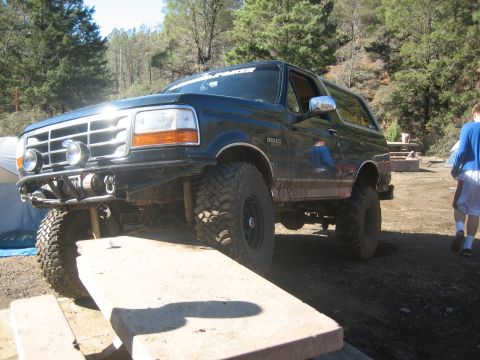 1995 Ford Bronco - A dark green Ford Bronco is positioned on a concrete picnic table in a wooded area.