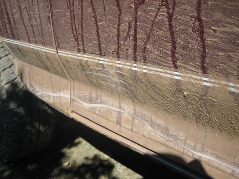 1995 Ford Bronco - Mud-splattered side panel of a vehicle with visible scratches and a white accent stripe.