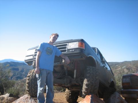 1995 Ford Bronco - A man poses next to a heavily modified black Ford Bronco, with another vehicle visible in the background.