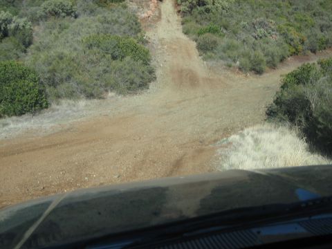 1995 Ford Bronco - A dirt path winds its way up a dry, brush-covered hillside under a clear sky.