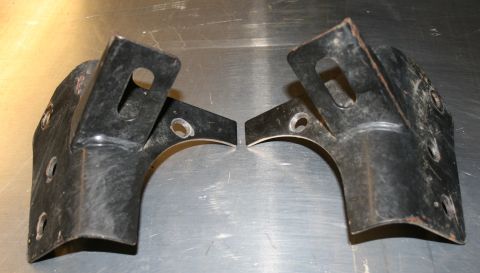 2003 Jeep TJ - Two metal brackets, likely for automotive use, are shown on a metallic surface.