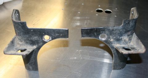 2003 Jeep TJ - Two metal brackets are shown on a reflective surface, likely automotive parts.