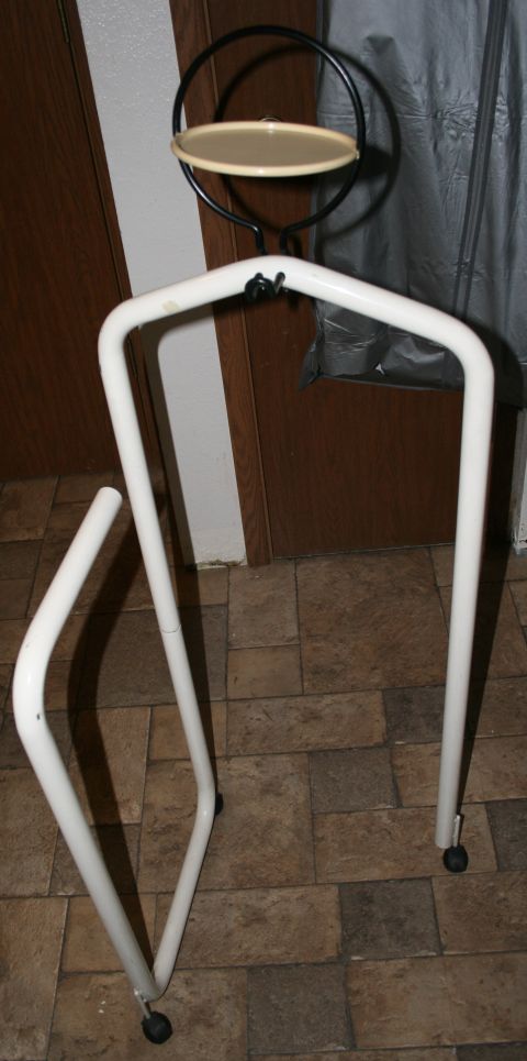 2003 Jeep TJ - White metal garment rack with a circular shelf and a detached leg.