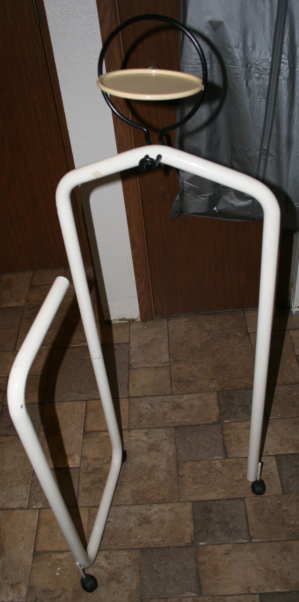 White metal garment rack with a circular shelf on top. One leg is detached