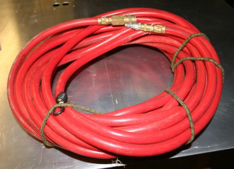 2003 Jeep TJ - A red air hose is coiled on a metallic surface, secured with a strap and a metal ring.