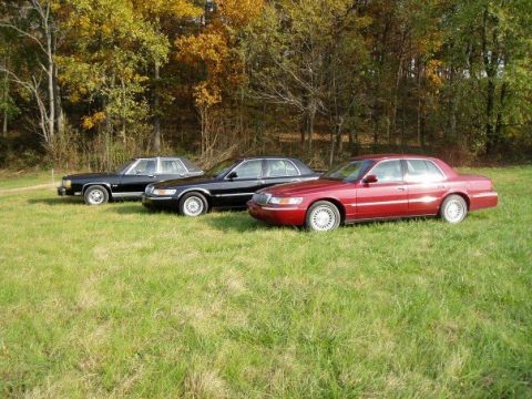 2001 Mercury Grand Marquis - Three Mercury Grand Marquis sedans are parked in a grassy field during autumn.