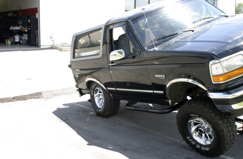 Black Ford Bronco, side view, showing the front fender and door. Has a 'Bronco' badge