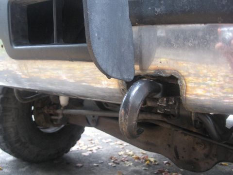 1996 Ford Bronco - Close-up of a 1996 Ford Bronco's front bumper, showing a black tow hook mounted in a corroded opening.