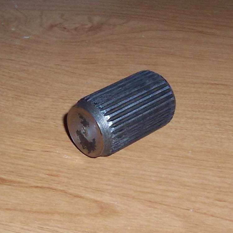 Metal splined shaft with a worn end, lying on a wooden surface