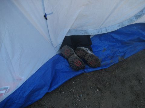 1966 Jeep CJ5 - A person's legs and feet are visible inside a tent, resting on a blue tarp.