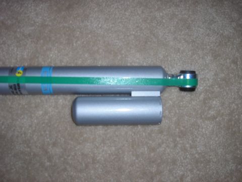 1996 Ford Bronco - A silver shock absorber with a green band and blue markings is shown against a carpeted background.