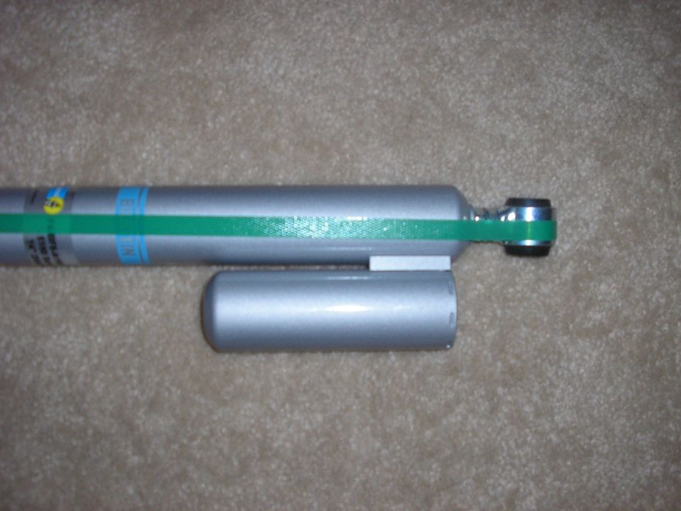 Silver shock absorber with green band and blue markings. Another silver cylinder is attached
