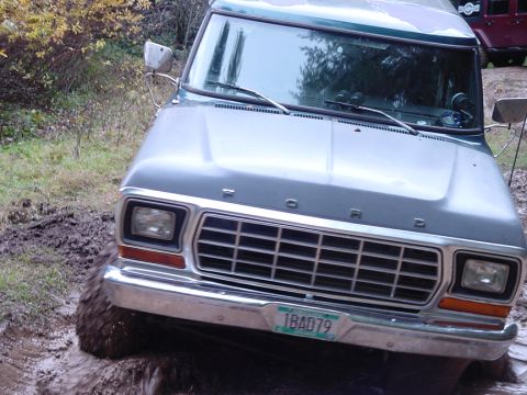1979 Ford Bronco - This 1979 Ford Bronco is navigating a muddy terrain, with its front grille and license plate clearly visible.