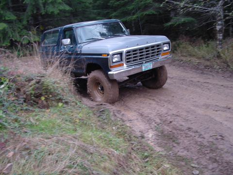 1979 Ford Bronco - This Ford Bronco is navigating a challenging muddy terrain on a wooded path.