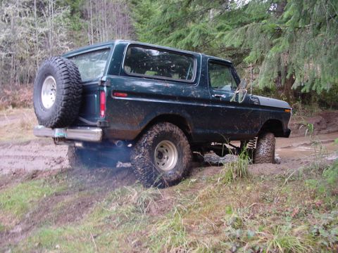 1979 Ford Bronco - Muddy 1978 Ford Bronco is stuck off-road, emitting exhaust smoke.