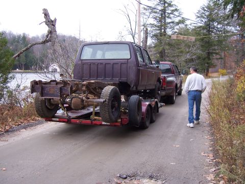 1996 Ford Bronco - A truck chassis is being transported on a trailer, followed by another pickup truck.