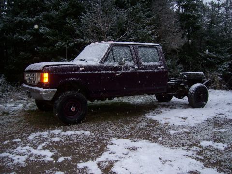 1996 Ford Bronco - A dark red crew cab pickup truck chassis sits in a snowy wooded area.