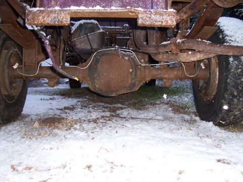 1996 Ford Bronco - Close-up of a heavily rusted truck's rear axle and suspension components covered in snow.