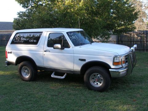 1992 Ford Bronco - A white 1992 Ford Bronco 4x4 is parked on a grassy lawn with "For Sale" signs on its windows.
