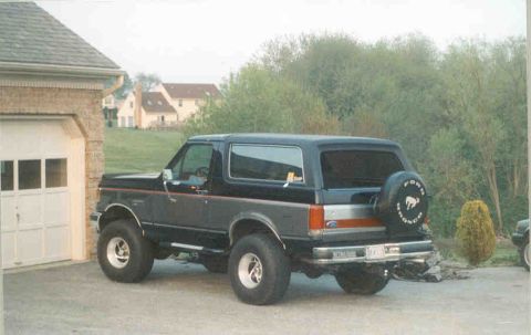1990 Ford Bronco - This Ford Bronco is parked in front of a garage with houses in the background.