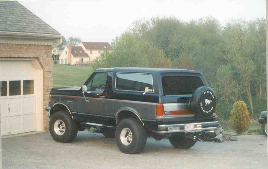 Black Ford Bronco parked in driveway, spare tire on back