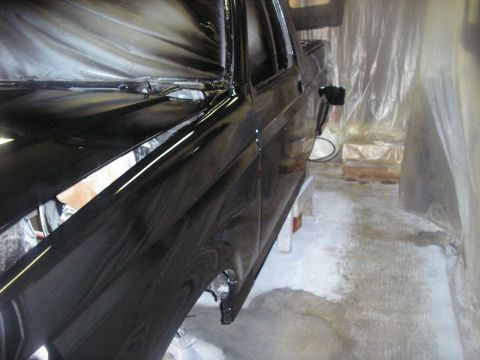 1987 Ford Bronco - A black Ford Ranger truck bed is covered in plastic and being painted in a spray booth.