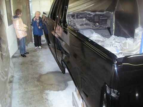 1987 Ford Bronco - Interior of a black SUV is covered in plastic sheeting, with two children observing the work.