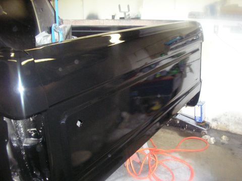 1987 Ford Bronco - Black pickup truck bed is being worked on, supported by a jack.