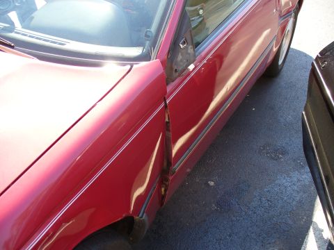 1991 Ford Probe - The driver's side door and fender of a red 1991 Ford Probe show severe damage.