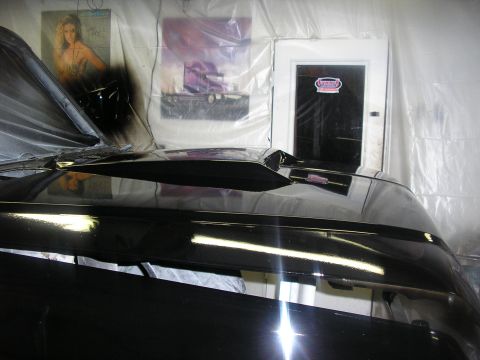 1987 Ford Bronco - A black vehicle's hood and fender are visible, covered in plastic sheeting, possibly during a paint job.