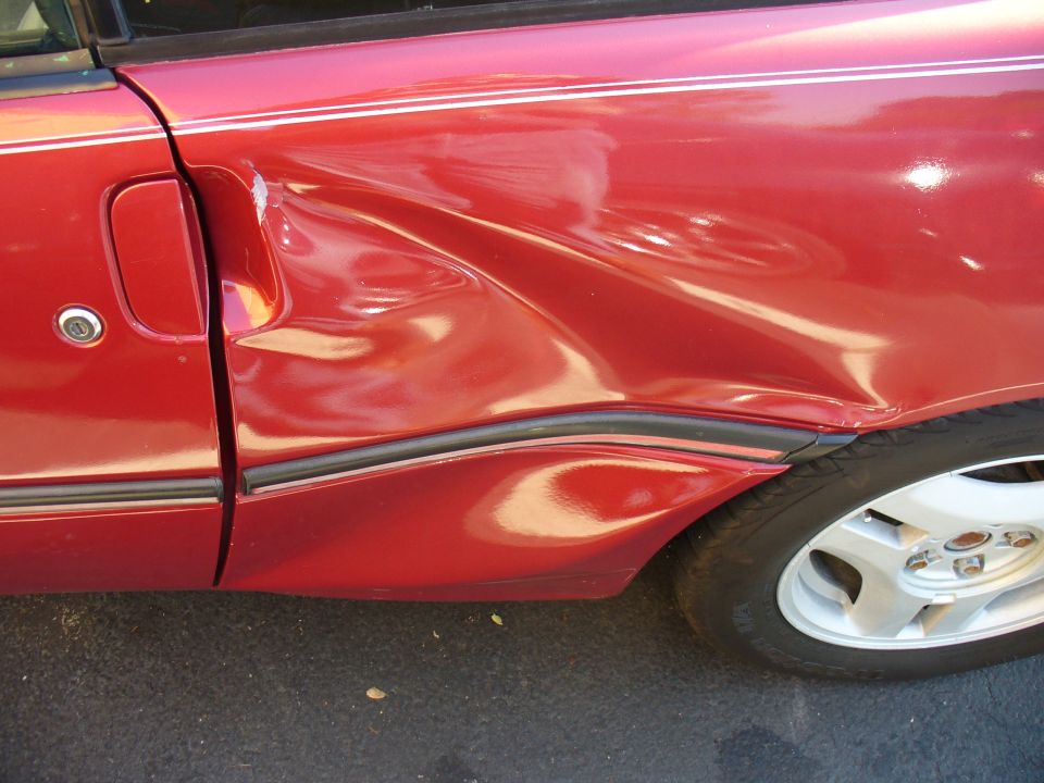 Red 1991 Ford Probe side panel with significant damage to the door and fender