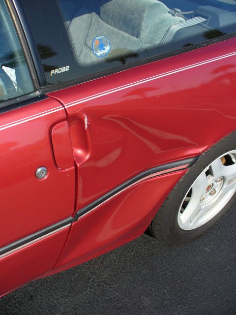 1991 Ford Probe - This 1991 Ford Probe shows significant damage to its side door, as indicated by the visible dent and the 'PROBE' badging on the window.